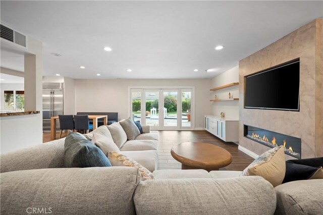 living room with dark wood-type flooring and a large fireplace