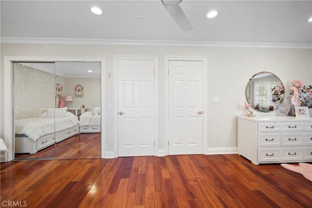 unfurnished bedroom featuring ceiling fan, dark wood-type flooring, crown molding, and two closets