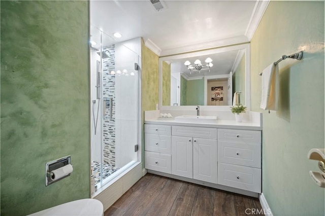 bathroom with toilet, vanity, hardwood / wood-style floors, ornamental molding, and a shower with door