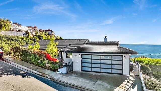 1380 Skyline Dr, Laguna Beach, CA 92651 - contemporary home with a tile roof, stucco siding, an attached garage, a water view, and a chimney