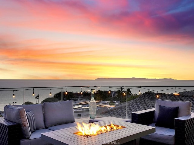 patio terrace at dusk with an outdoor fire pit and a water and mountain view