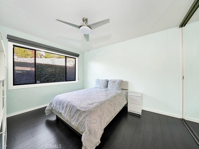 bedroom featuring ceiling fan, dark hardwood / wood-style flooring, and a closet