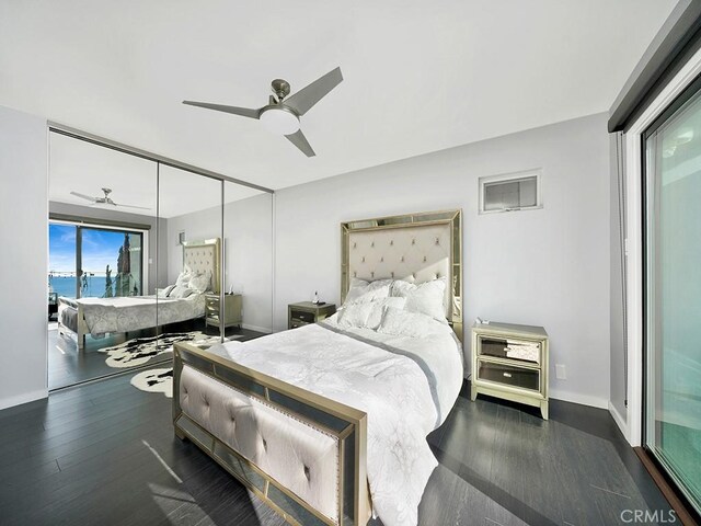 bedroom with ceiling fan, dark hardwood / wood-style flooring, a closet, and a water view