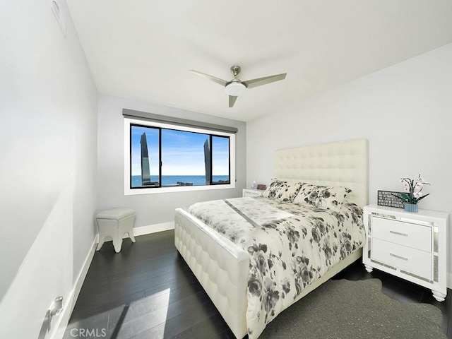 bedroom with ceiling fan, a water view, and dark hardwood / wood-style floors