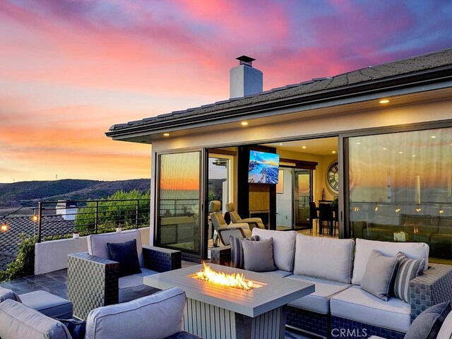 patio terrace at dusk with a mountain view and an outdoor living space with a fire pit