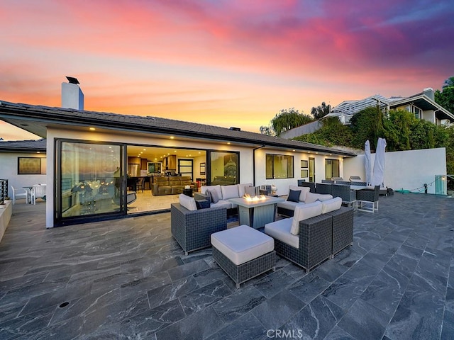 patio terrace at dusk featuring an outdoor living space with a fire pit