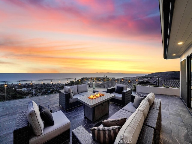 patio terrace at dusk featuring an outdoor living space with a fire pit and a water view