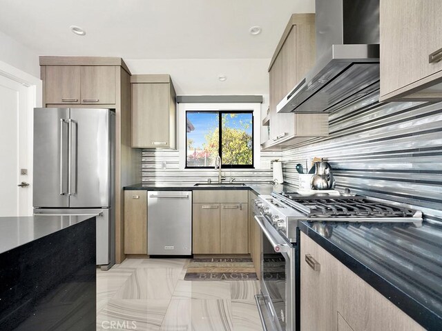 kitchen with sink, premium appliances, light brown cabinets, and wall chimney exhaust hood