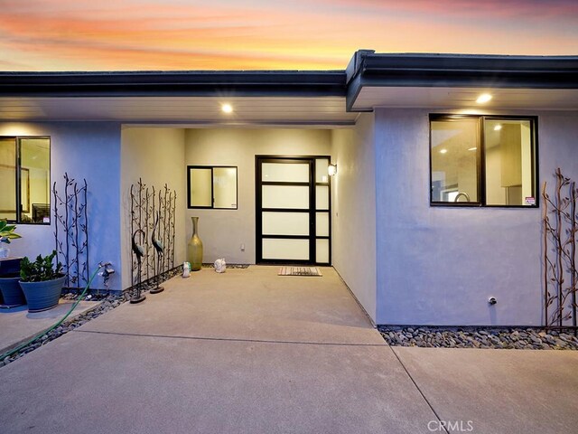 exterior entry at dusk featuring a patio