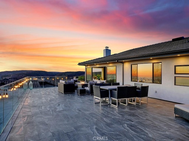 patio terrace at dusk featuring an outdoor living space and a mountain view