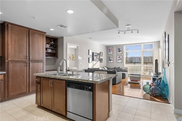 kitchen featuring dishwasher, sink, light tile patterned flooring, a kitchen island with sink, and light stone countertops