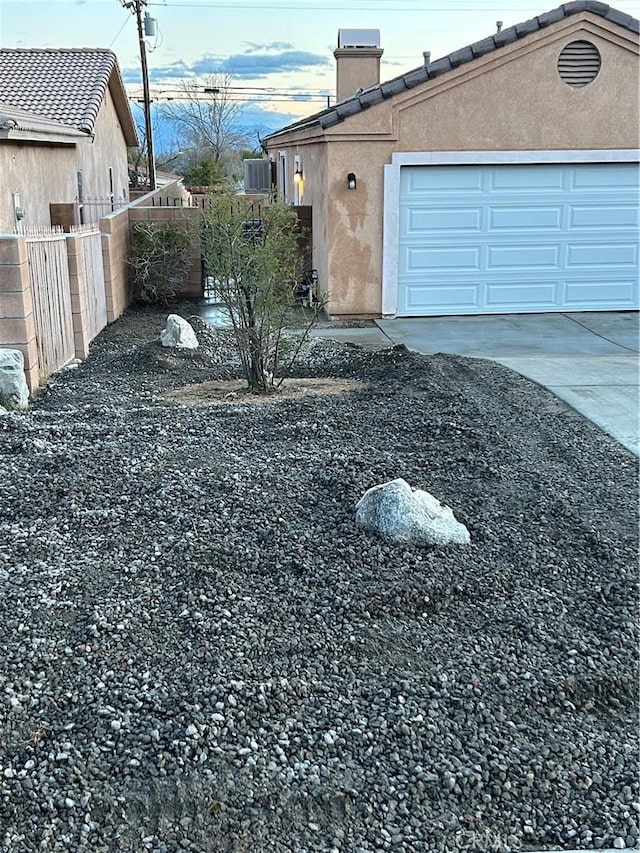 66263 6th St, Desert Hot Springs, CA 92240 - view of home's exterior featuring a chimney, fence, stucco siding, an attached garage, and concrete driveway