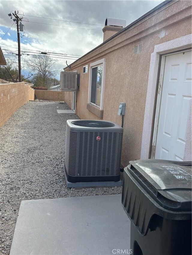 66263 6th St, Desert Hot Springs, CA 92240 - view of property exterior with stucco siding, a fenced backyard, a chimney, and central AC unit