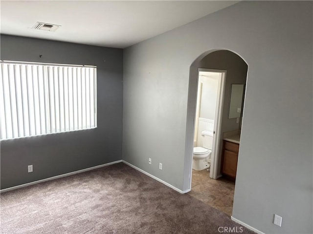 unfurnished bedroom with connected bathroom and carpet