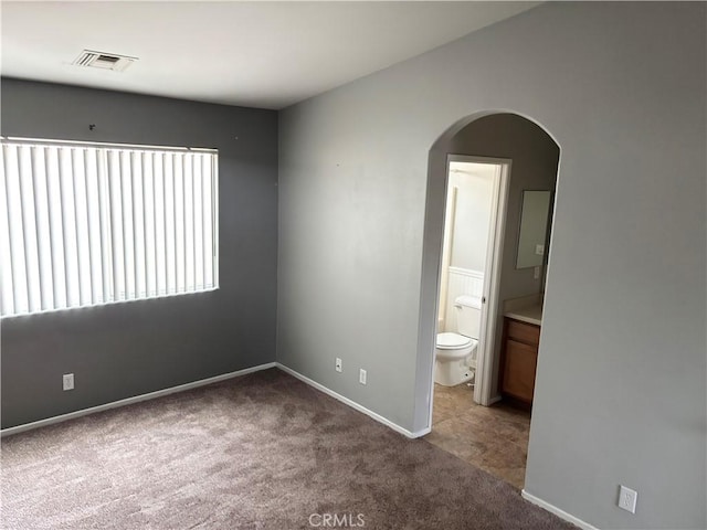 66263 6th St, Desert Hot Springs, CA 92240 - unfurnished bedroom featuring carpet, visible vents, arched walkways, baseboards, and ensuite bathroom
