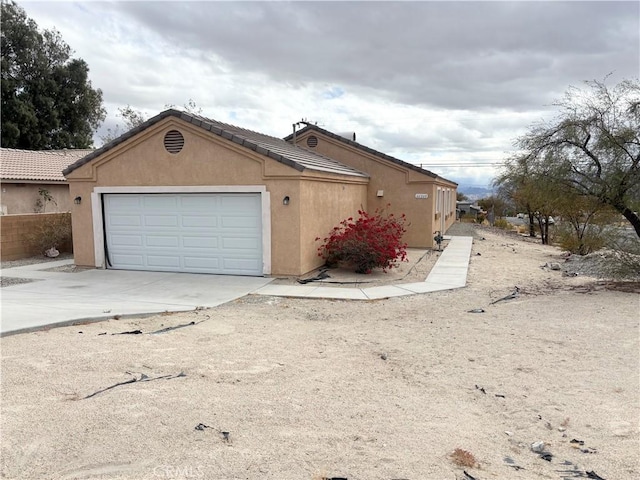 66263 6th St, Desert Hot Springs, CA 92240 - view of side of property with concrete driveway, an attached garage, and stucco siding