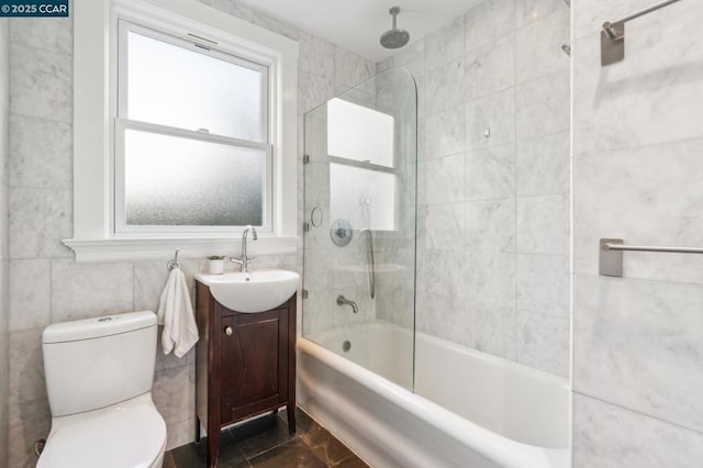 full bathroom with vanity, toilet, tiled shower / bath combo, and tile walls