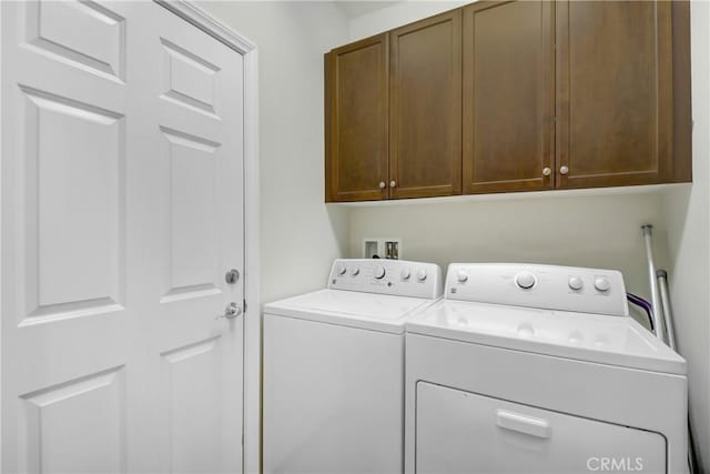 laundry room featuring washer and dryer and cabinets