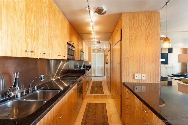 kitchen featuring decorative light fixtures, decorative backsplash, sink, track lighting, and dark stone counters