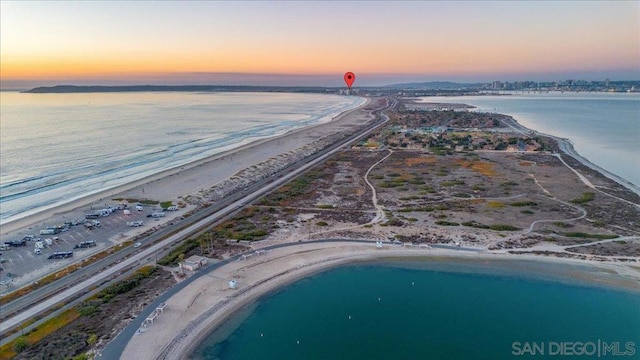 aerial view at dusk with a beach view and a water view