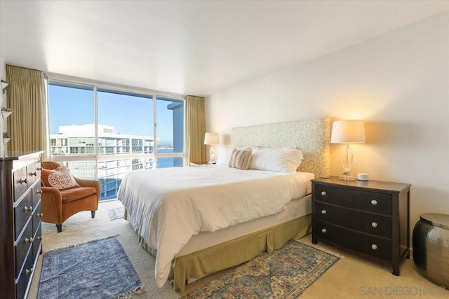 bedroom featuring light colored carpet and floor to ceiling windows