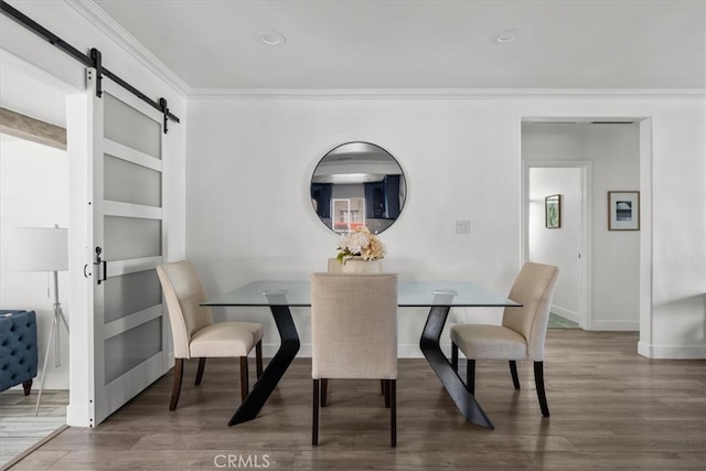 dining space featuring crown molding, a barn door, and dark hardwood / wood-style floors