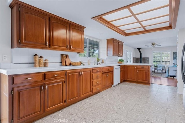 kitchen featuring ceiling fan, white dishwasher, kitchen peninsula, and backsplash