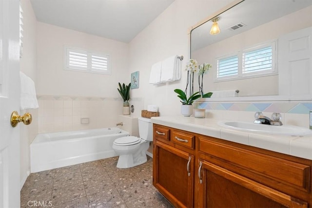 bathroom featuring vanity, toilet, and a washtub