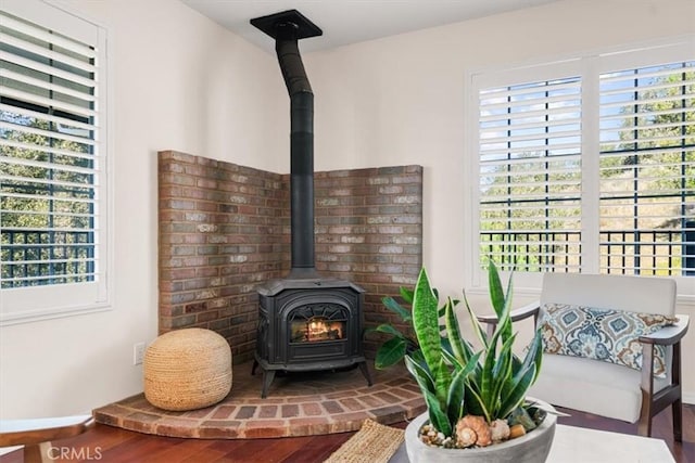 sitting room featuring plenty of natural light, wood-type flooring, and a wood stove