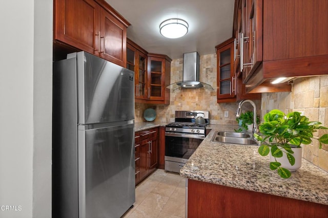 kitchen with light stone countertops, wall chimney range hood, stainless steel appliances, sink, and backsplash