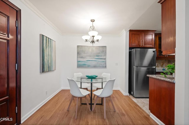 dining area with light wood-type flooring, a notable chandelier, and crown molding