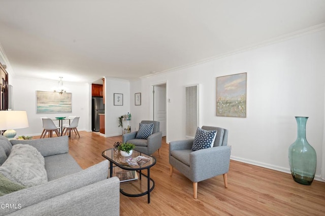 living room featuring a chandelier, crown molding, and light hardwood / wood-style floors