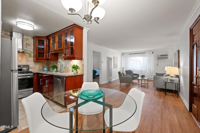 dining room featuring sink, a chandelier, light hardwood / wood-style flooring, crown molding, and a wall mounted air conditioner