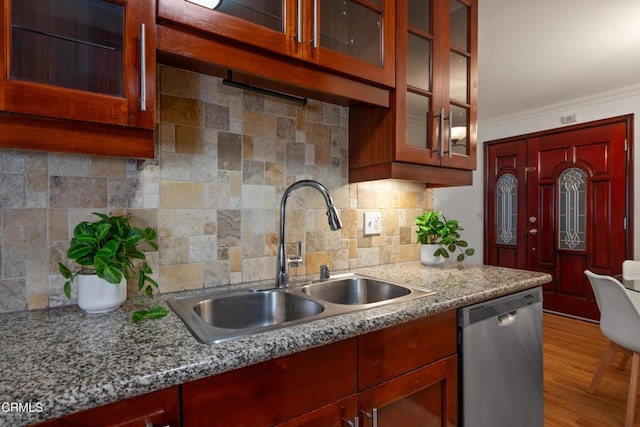 kitchen featuring light stone countertops, sink, backsplash, stainless steel dishwasher, and crown molding