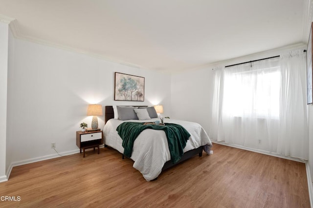 bedroom with ornamental molding and light hardwood / wood-style flooring