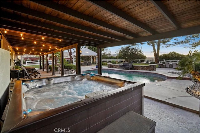 pool at dusk with a patio and an outdoor hot tub