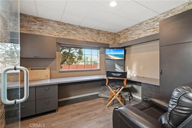 home office featuring a paneled ceiling, built in desk, and light wood-type flooring