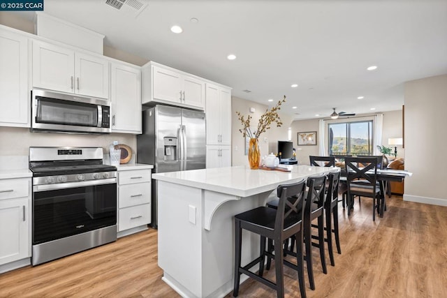 kitchen featuring ceiling fan, appliances with stainless steel finishes, white cabinetry, and a kitchen island