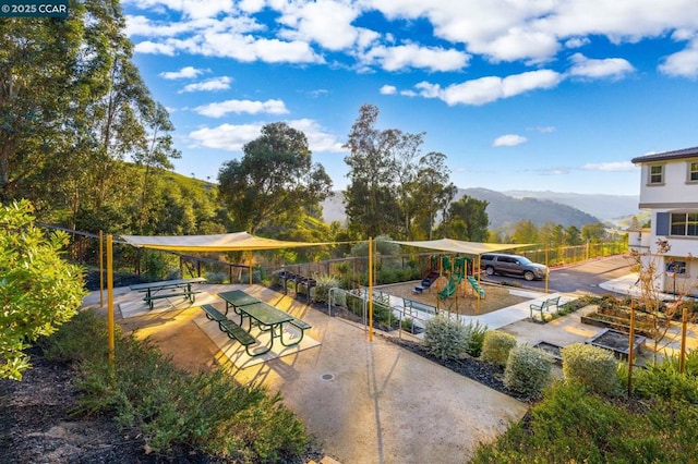 surrounding community with a playground and a mountain view