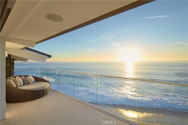 balcony at dusk featuring a water view