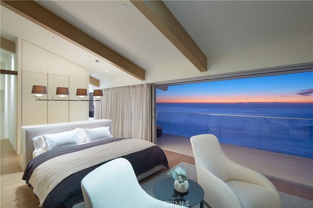 bedroom with beam ceiling, light hardwood / wood-style floors, and a water view