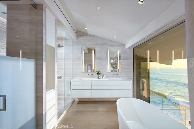 bathroom with lofted ceiling, hardwood / wood-style flooring, tile walls, vanity, and separate shower and tub