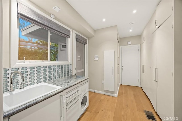 kitchen featuring sink, backsplash, white cabinets, and light hardwood / wood-style flooring