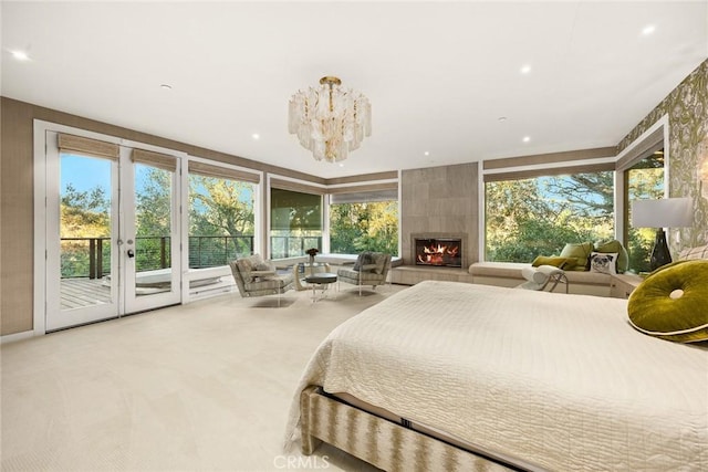 carpeted bedroom with multiple windows, a tile fireplace, access to outside, and an inviting chandelier