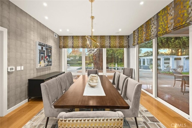 dining area with light wood-type flooring and an inviting chandelier