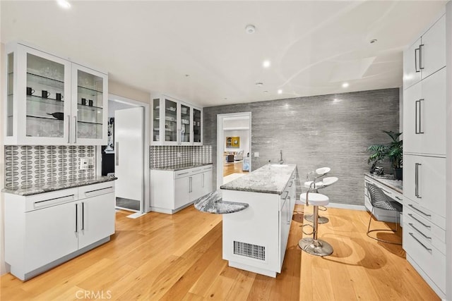 kitchen featuring backsplash, white cabinetry, a center island, and a breakfast bar