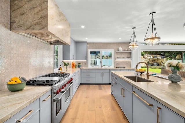 kitchen with custom exhaust hood, light stone countertops, sink, and decorative light fixtures