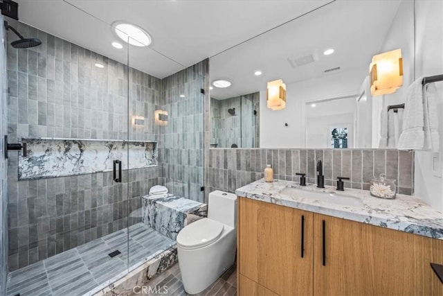 bathroom featuring toilet, a shower with shower door, tasteful backsplash, tile walls, and vanity