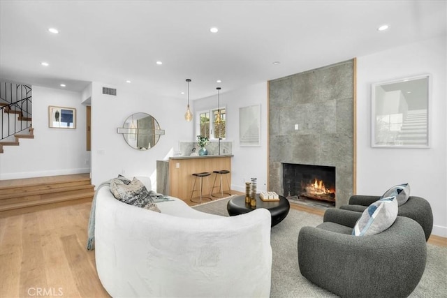 living room featuring a tile fireplace and light wood-type flooring