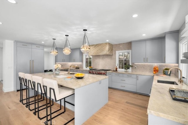 kitchen featuring sink, gray cabinetry, decorative light fixtures, light wood-type flooring, and a kitchen island